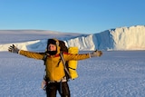 Gemma Woldendorp holds out her arms while wearing a yellow jacket at Mawson research station in Antarctica