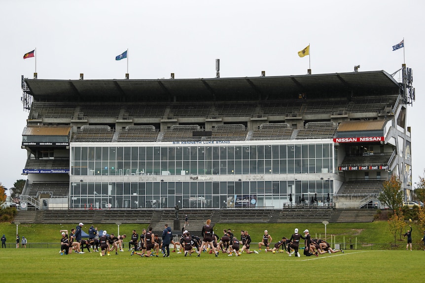 A wide shot of an old grandstand, with players training in front of it.