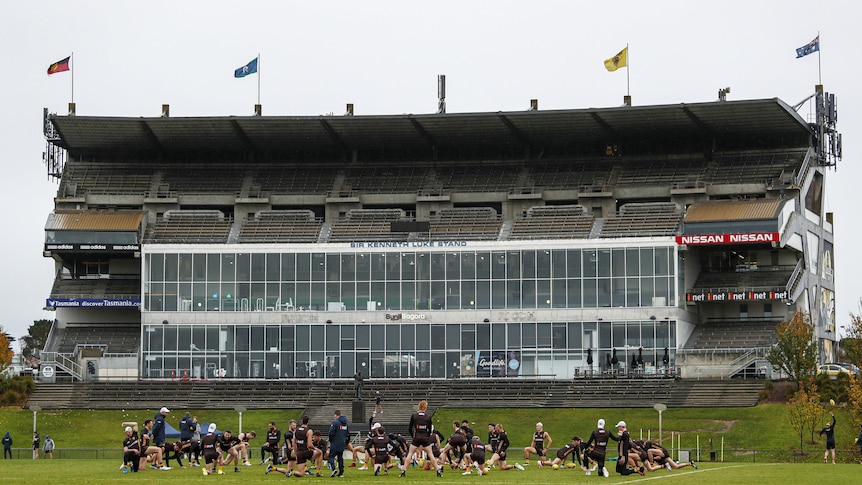 A wide shot of an old grandstand, with players training in front of it.