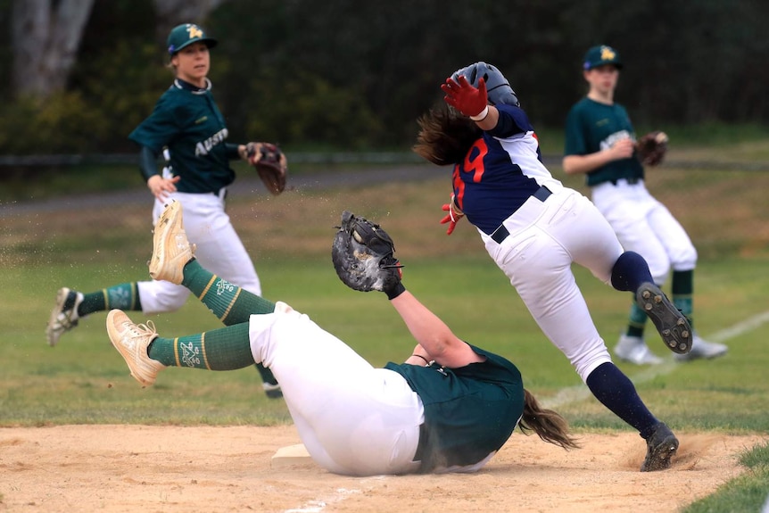 A runner avoids being tagged as she slides into base.
