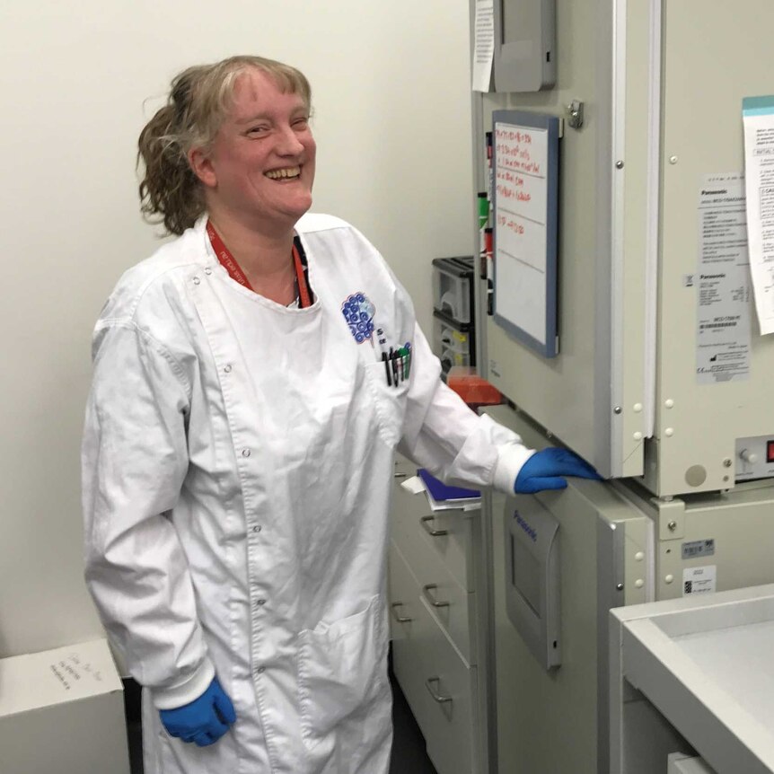 Neuroscientist Dr Jo-Maree Courtney in her lab coat in front of a fridge full of stem human cells