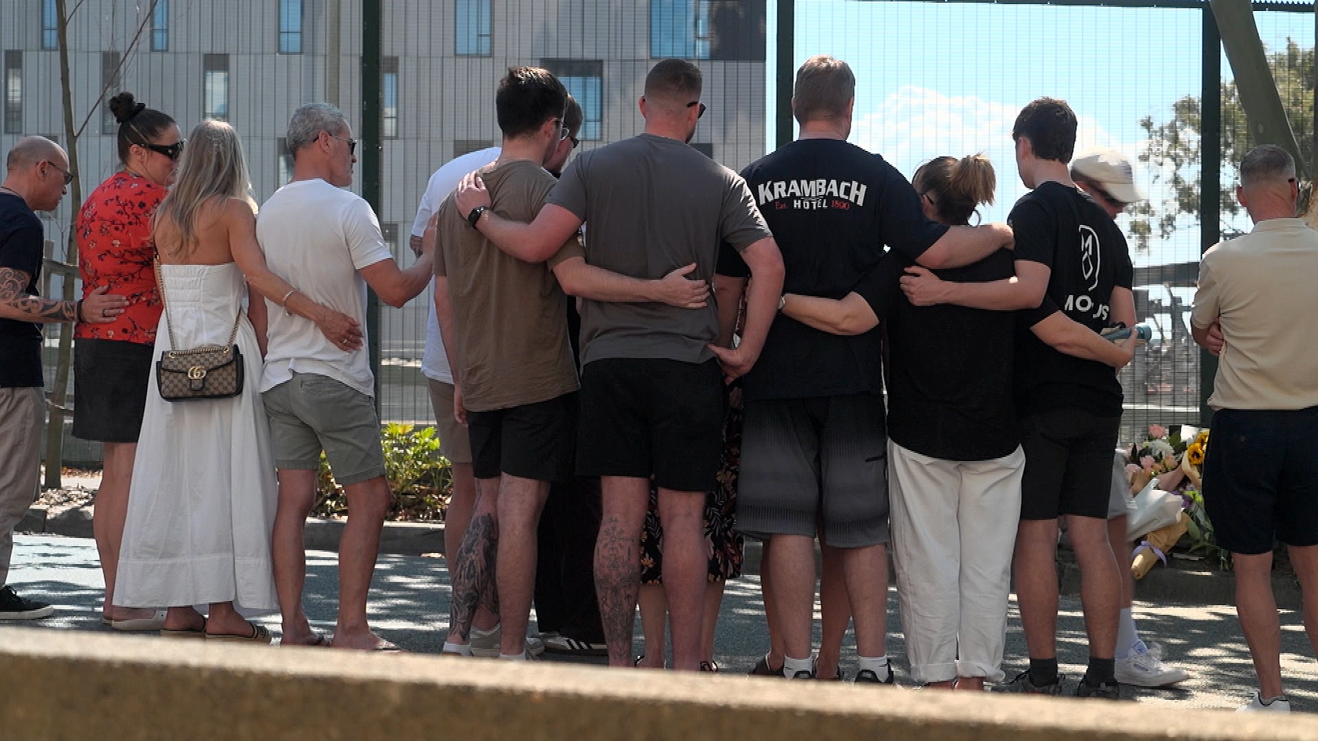 a group of people all hugging each other at the site where a young police officer died in a crash