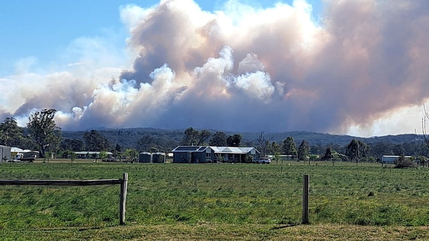 A house on a semi-rural block with a bushfire burning in the background.