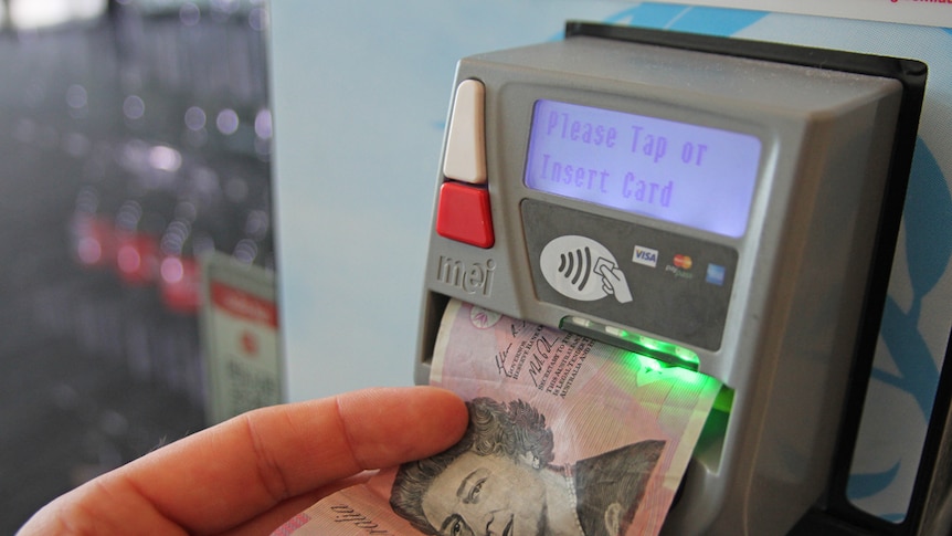 A hand puts money into a vending machine