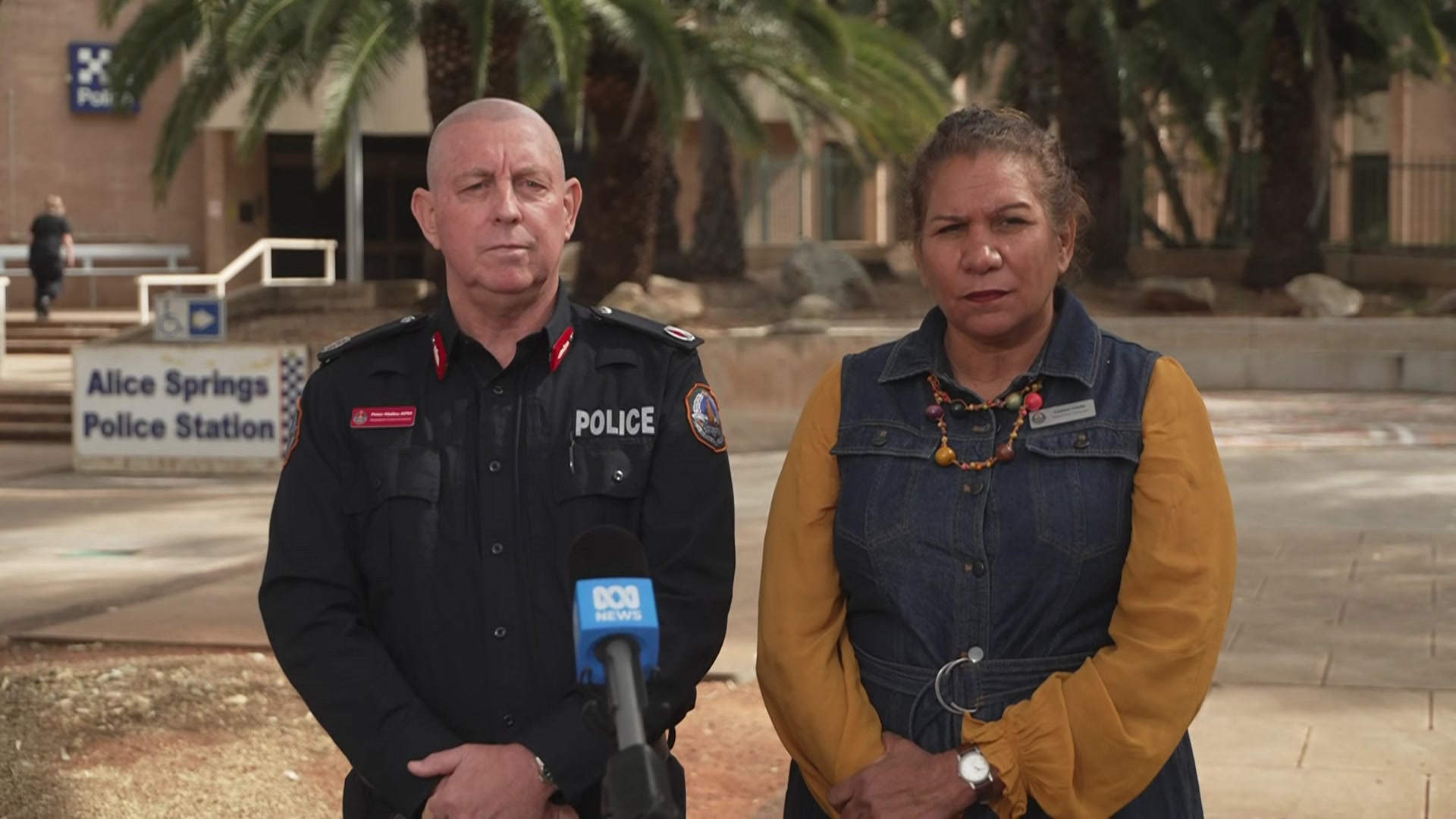 A police officer in uniform and a woman in civilian clothes outside a police station