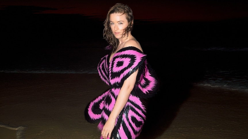 Megan Washington standing at a dimly lit beach.