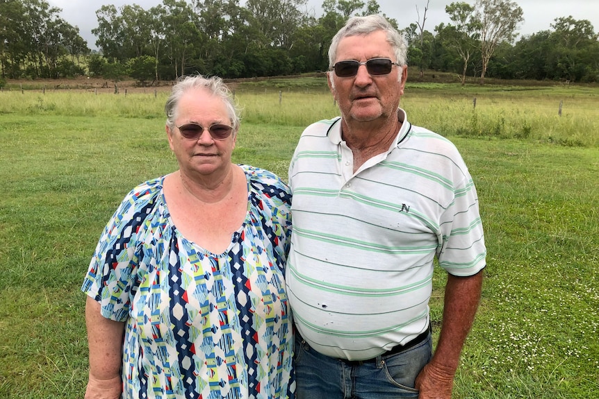 Woman and Man stand next to each other with green pasture behind them