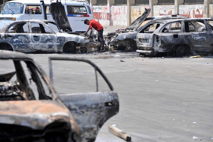 An Egyptian man inspects burnt out cars near Cairo University.