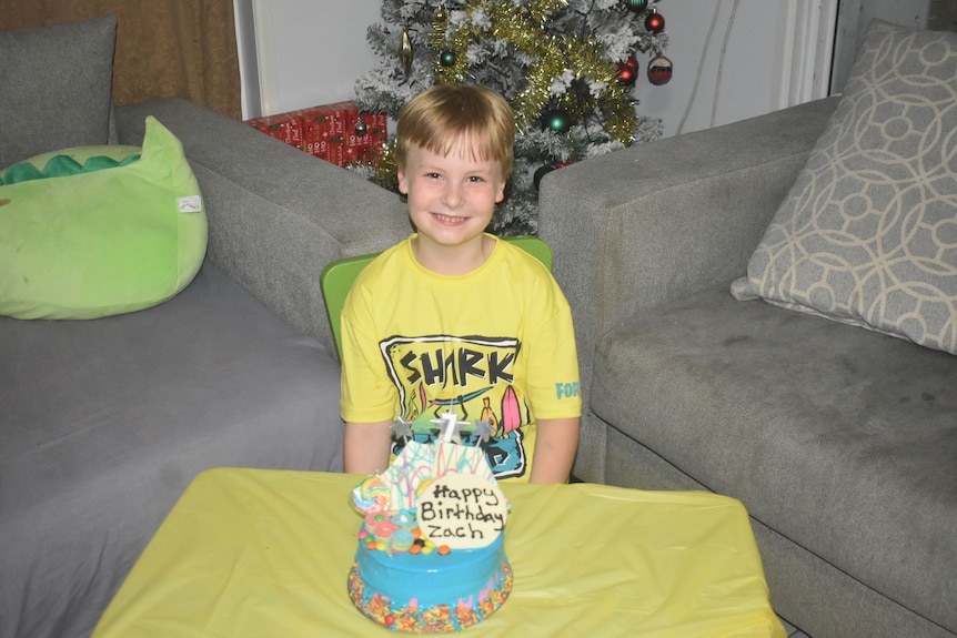 A boy with a birthday cake smiling for the camera
