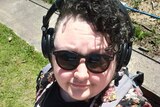 A man with curly hair wearing headphones in a selfie.