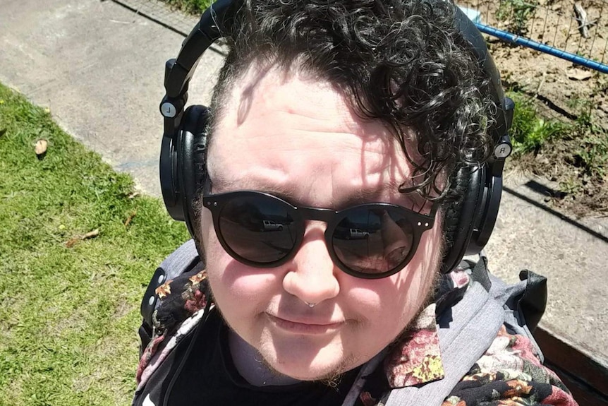 A man with curly hair wearing headphones in a selfie.