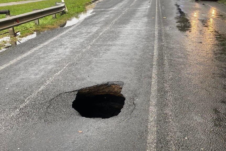 A large pothole in the middle of a surburban street.
