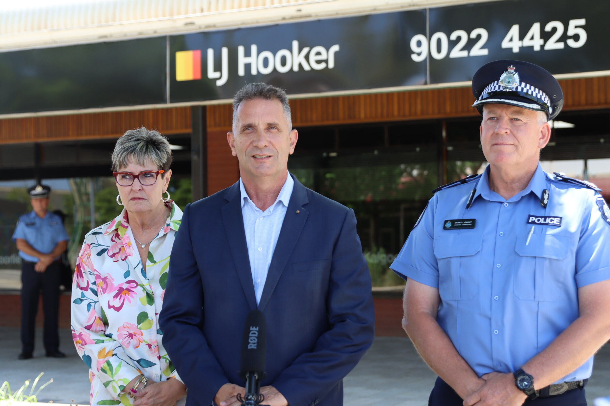 A woman and man stand next to a police officer