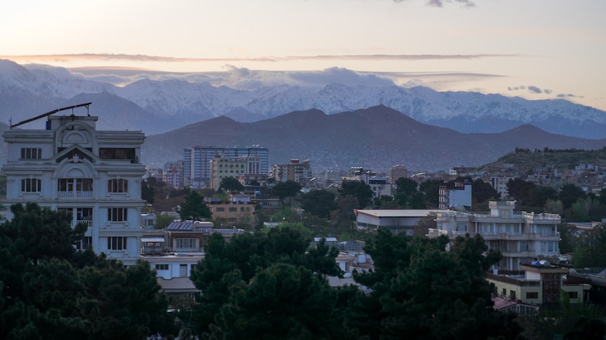 A city with snow covered mountains in the background.