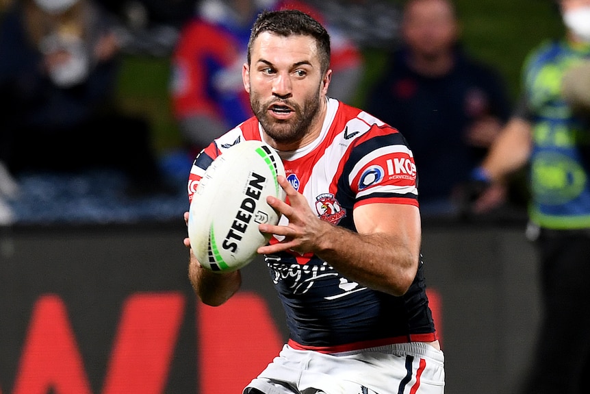 A Sydney Roosters NRL player runs with the ball in two hands.