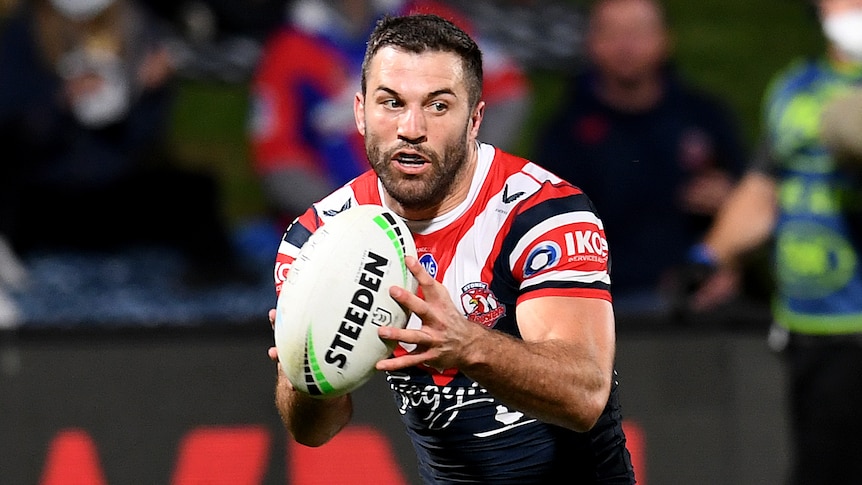 A Sydney Roosters NRL player runs with the ball in two hands.