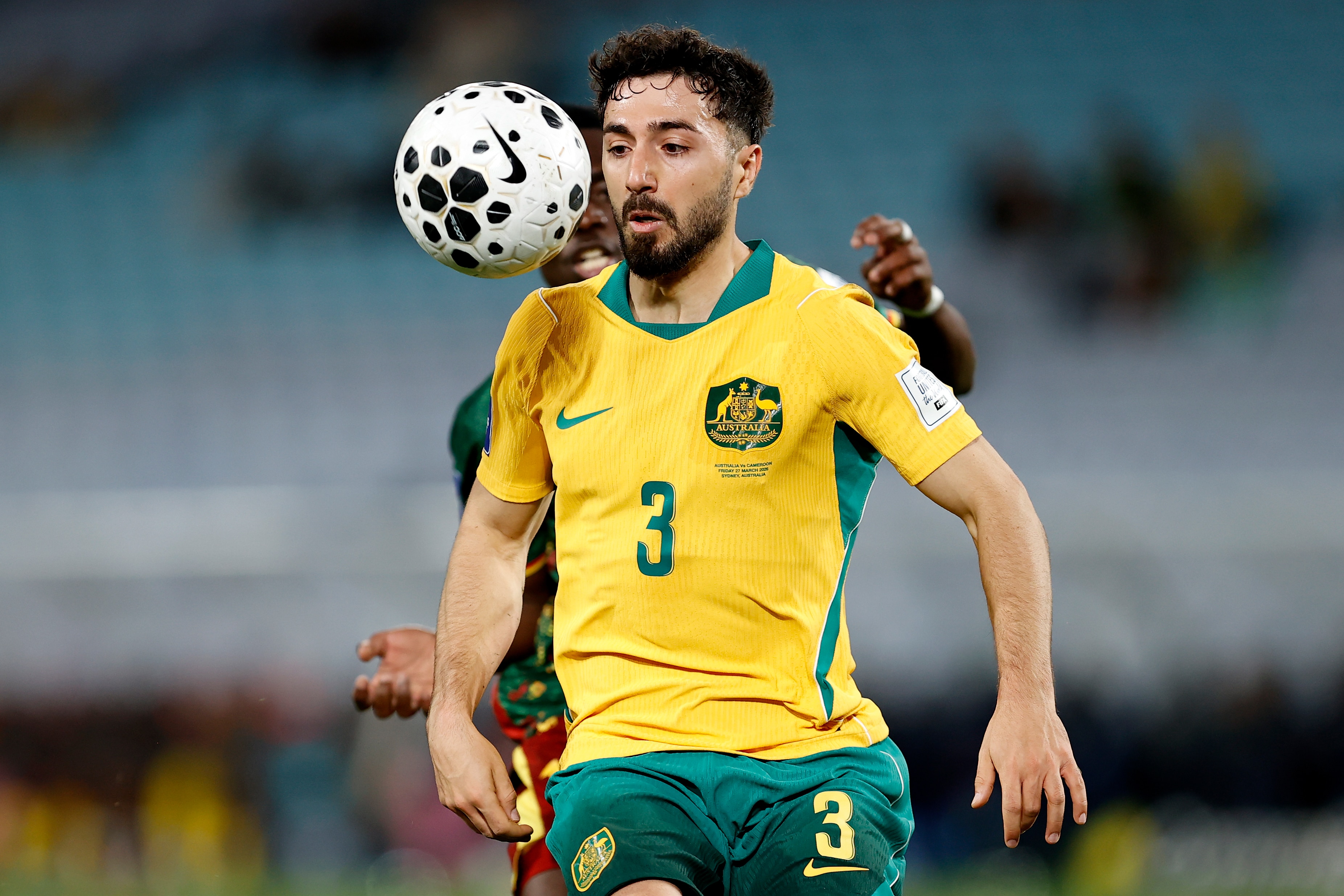 O jogador do Socceroos, Jacob Italiano, tem a bola na frente do rosto no ar durante um jogo