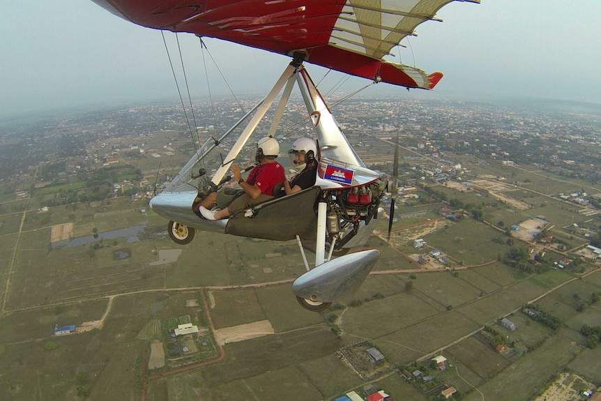 Rachel Lees in a two-person microlight aircraft flying over rural Cambodia.