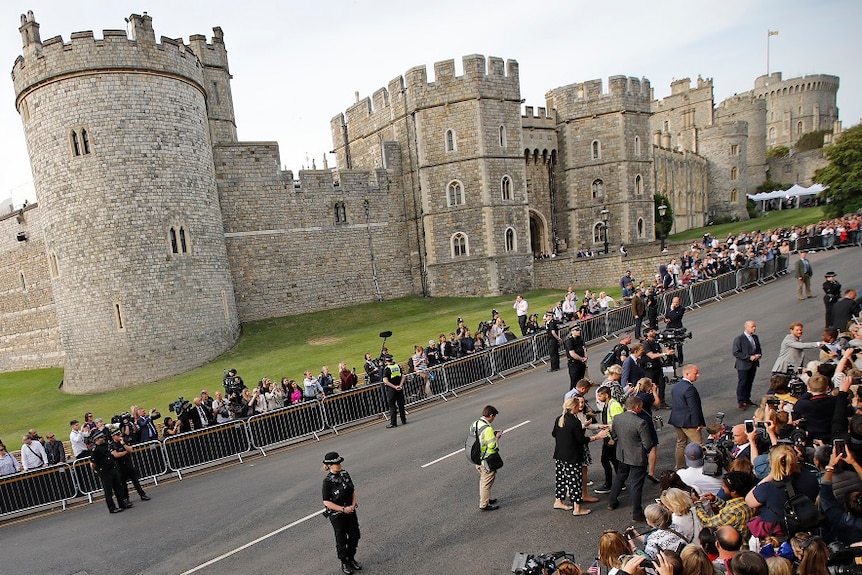 View from a distance showing packed crowds of media and wellwishers lining a street right outside Windsor Castle