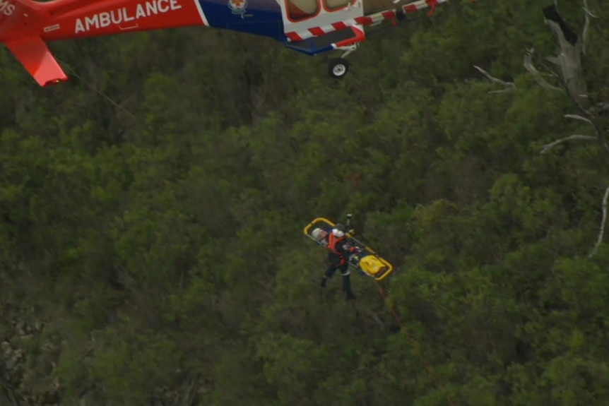 A man on a stretcher being airflited to an ambulance helicopter.