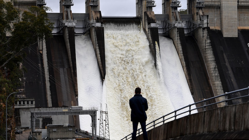 A person watches on as the Warragamba Dam spillway is seen outflowing in november 27 2021