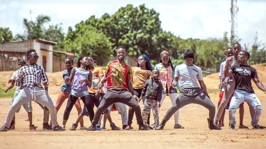 Dancehall enthusiast Alexx Mubanga leads a troupe in dance along a dusty street in Zambia.