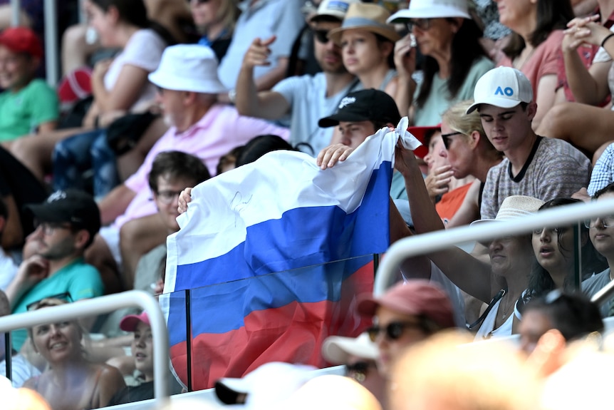 Fans hold up a Russian flag during an Australian Open tennis match between Andrey Rublev and Dominic Thiem.