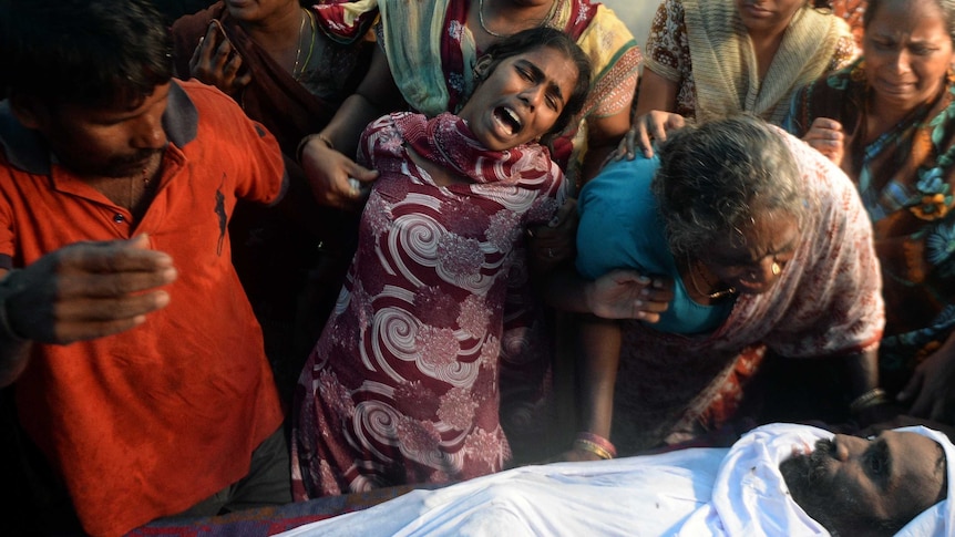 An Indian woman cries next to the body of a victim of toxic home-made liquor consumption in Mumbai