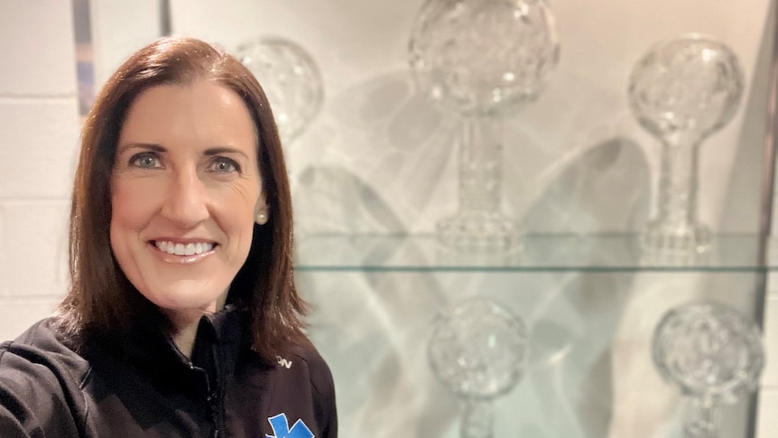 A woman stands in front of a trophy case