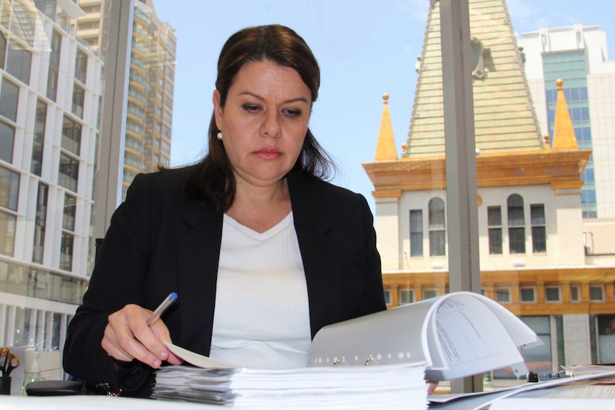 A woman examines legal documents while seated at a desk.