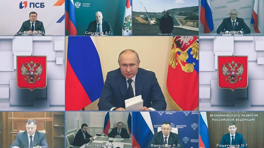 Multiple screens showing various Russian men in suits sitting at desks but the larger, centre screen shows Vladimir Putin.