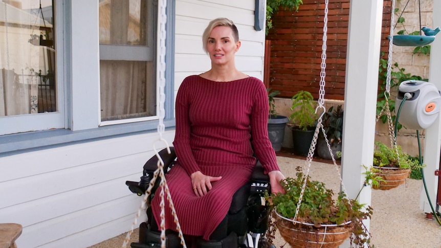 A woman in a burgundy dress in a wheelchair on her porch
