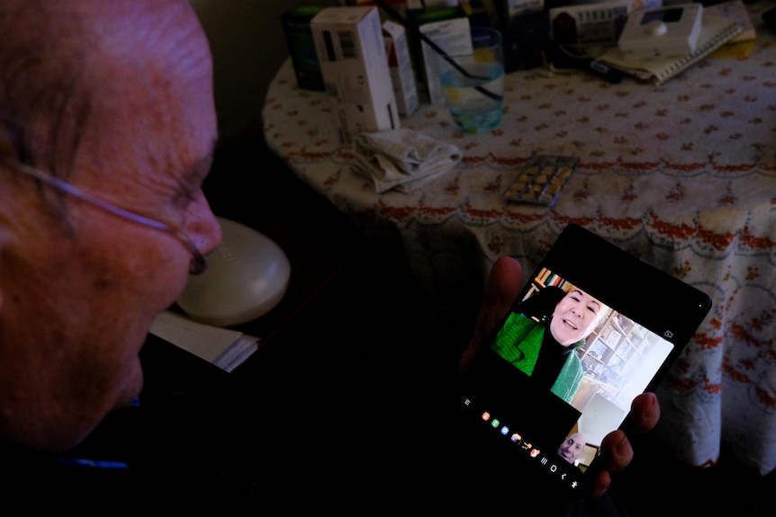 Un hombre con un respirador alrededor de la cara mira un monitor mientras hace una videollamada a una mujer. 
