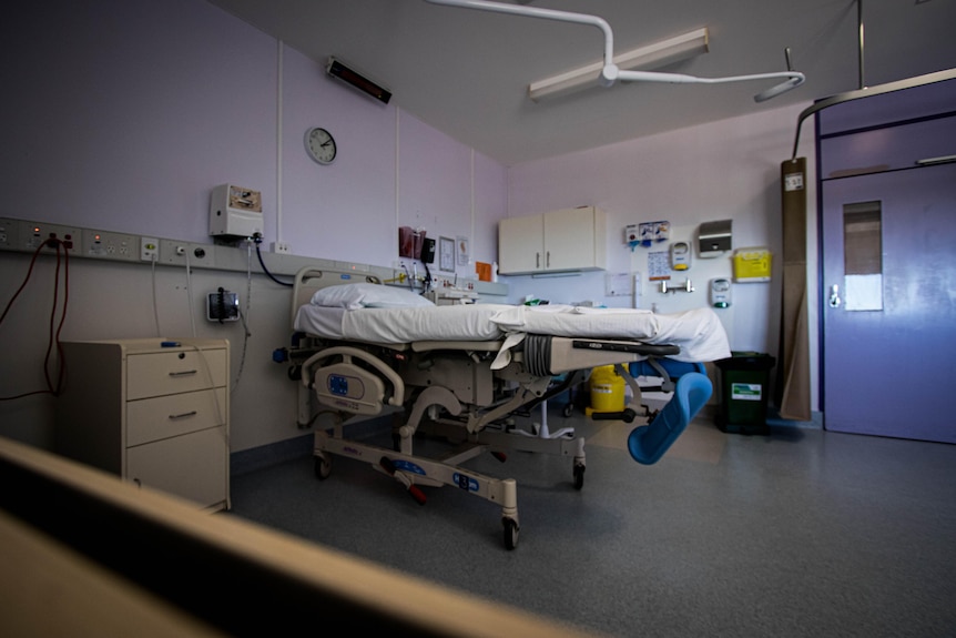 A clinical hospital room with a bed and medical supplies.