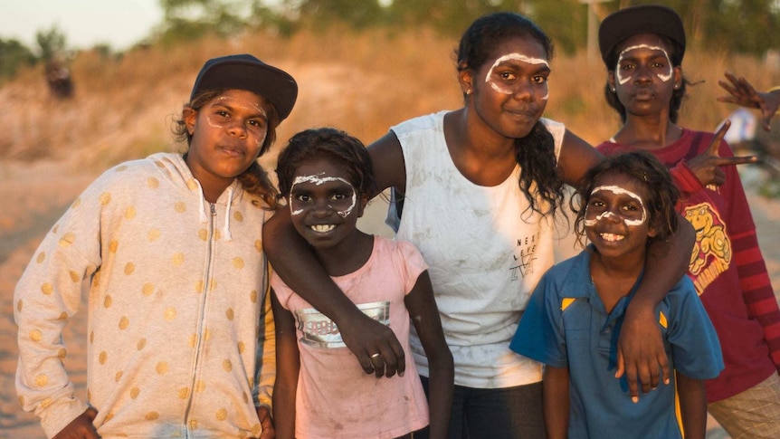 Youth in Belyuen with their faces painted on a beach at sunset