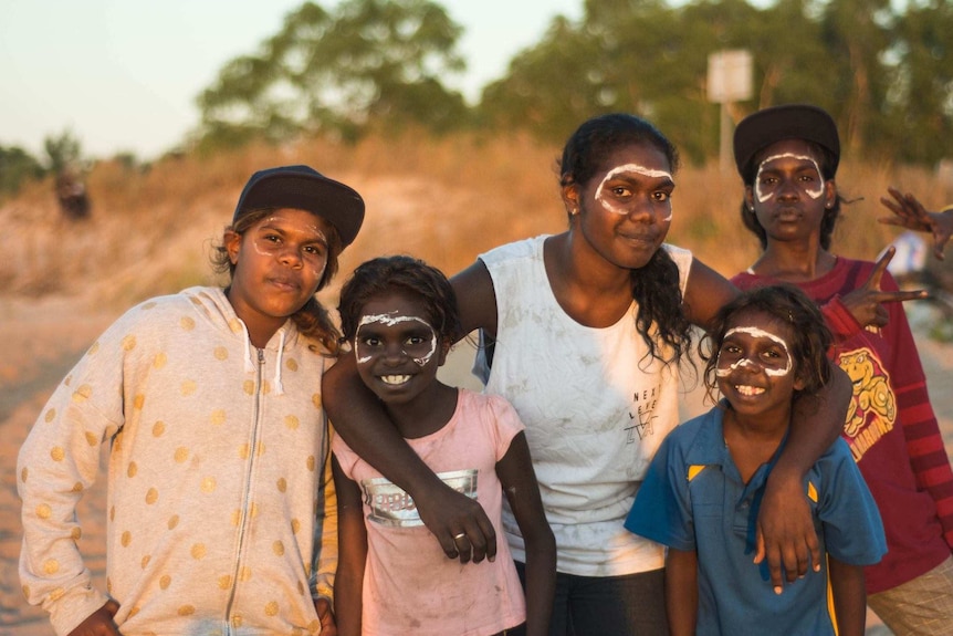 Youth in Belyuen with their faces painted on a beach at sunset