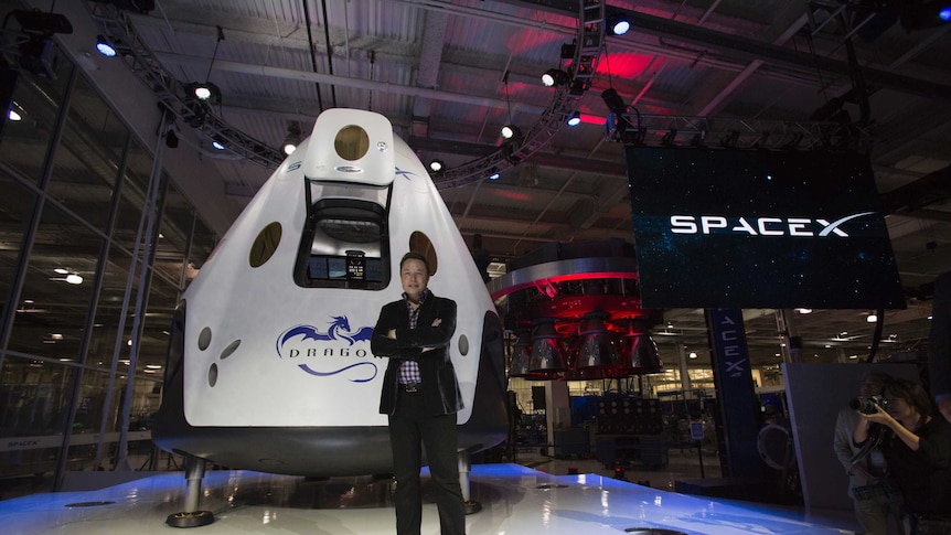 SpaceX CEO Elon Musk poses with the Dragon V2 spacecraft.