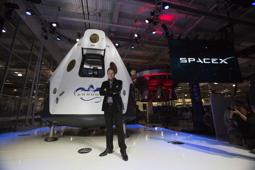 SpaceX CEO Elon Musk poses with the Dragon V2 spacecraft.