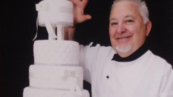 Farmer, Greg Smith standing next to a tiered wedding cake