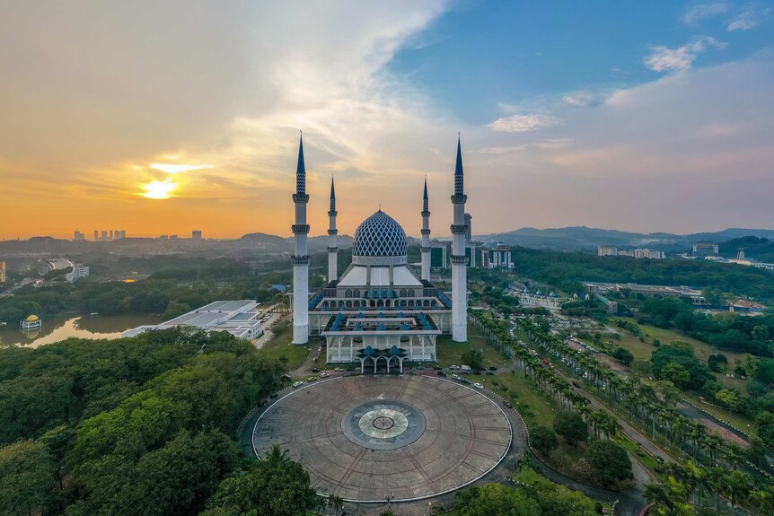 An aerial sunset view of Blue Mosque, the largest mosque in Malaysia. The city of Shah Alam is seen in the background.