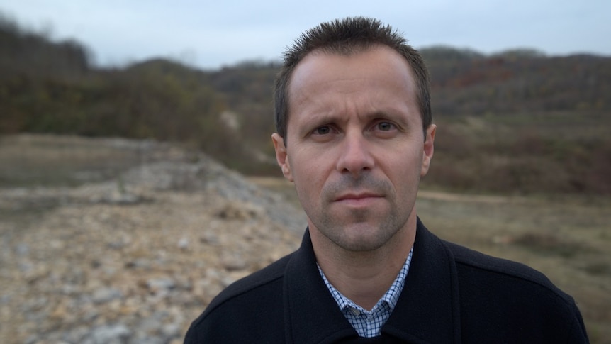 Nedzad Avdic stands in the fields and stares into the camera.