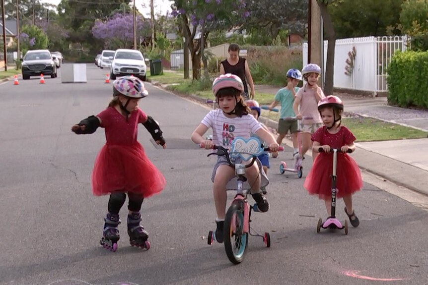 Children cycling and roller-skating on a suburban street