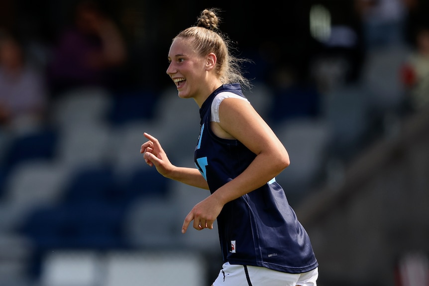 Montana Ham smiles as she runs during an under-18 AFLW game.