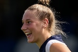 Montana Ham smiles as she runs during an under-18 AFLW game.