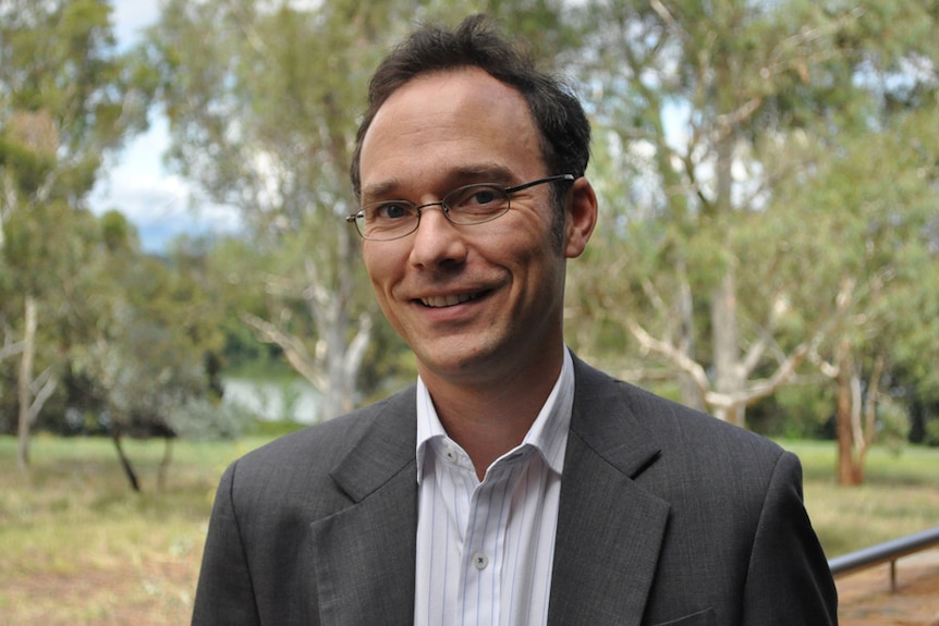 Frank Jotzo smiles at the camera. Trees are in the background.