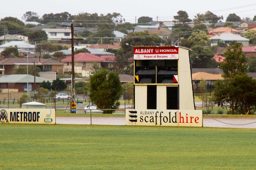 An empty football scoreboard at the edge of a suburban oval