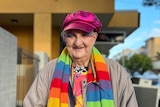Michelle Rose Turnbull smiling while wearing a bright pink hat and rainbow scarf