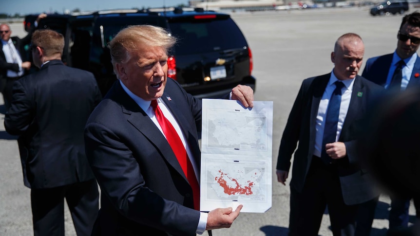 US President Donald Trump holds two maps of Syria.
