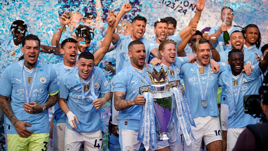 Manchester City players hold up a trophy