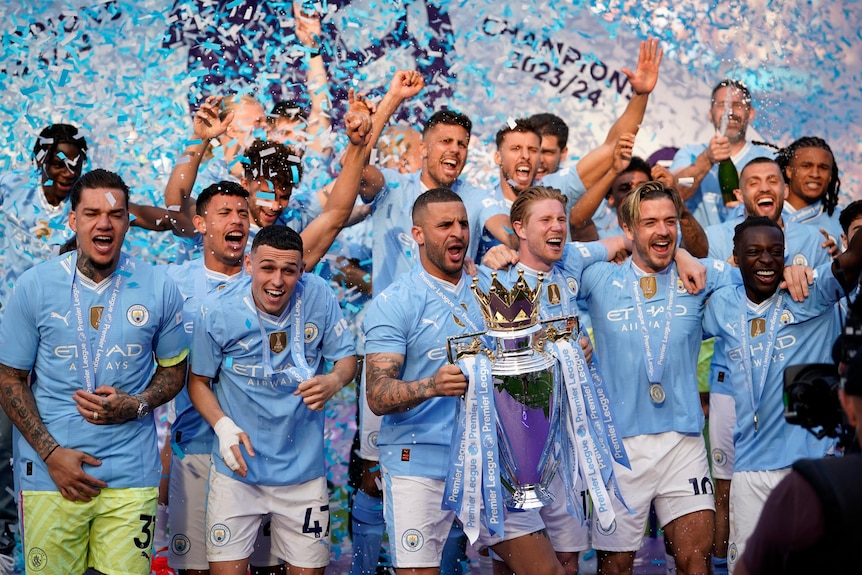 Manchester City players hold up a trophy